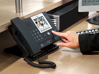 A multi-tenant guard station set on a concierge desk being used to screen visitors into an apartment or multi use building. The screen shows a modern happy family to whom the concierge is about to grant entry.
