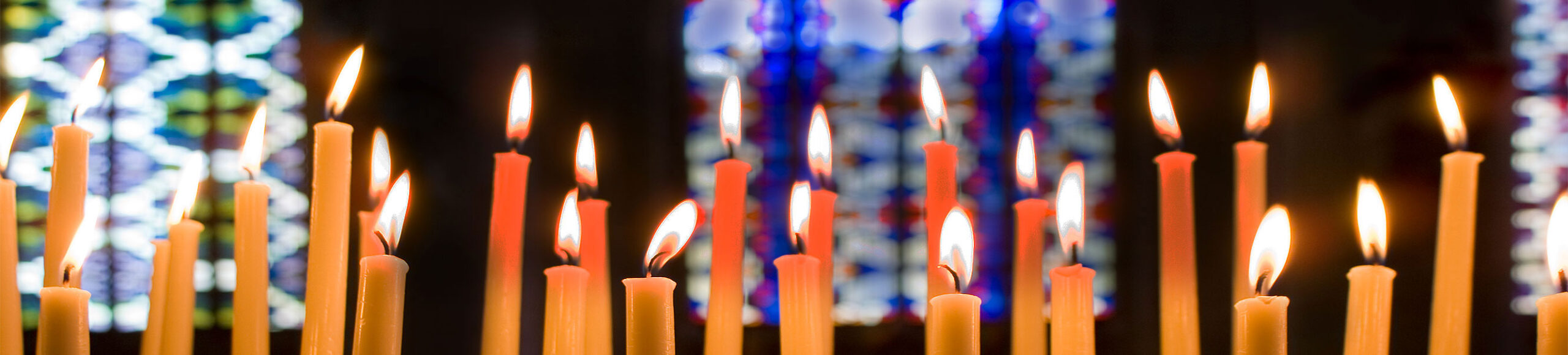 Stained glass Image with lit candles in a church environment.|African American senior citizens talking in church.|Image of stained glass windows at a house of worship and candles