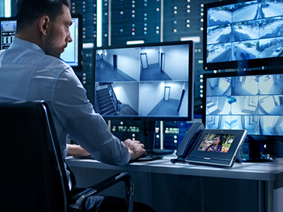 IX Series 2 two being used to enhance and expand a security center. The IX-MV7-HB screen shows an young lady looking aprrehensive while the security operation center's larger monitor's show the surrounding area.